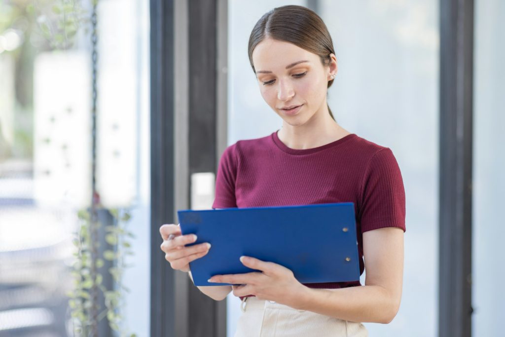 Boring young business canada american business woman holding document file and looking at camera