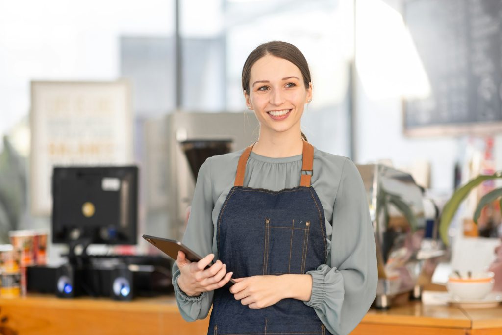 Open small business, Happy america, canada, woman in an apron standing near a bar counter coffee sho